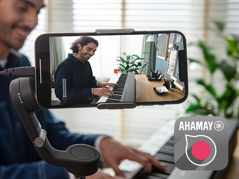 A view of the Yamaha Rec'n'Share app icon and a person taking a smartphone video of them playing