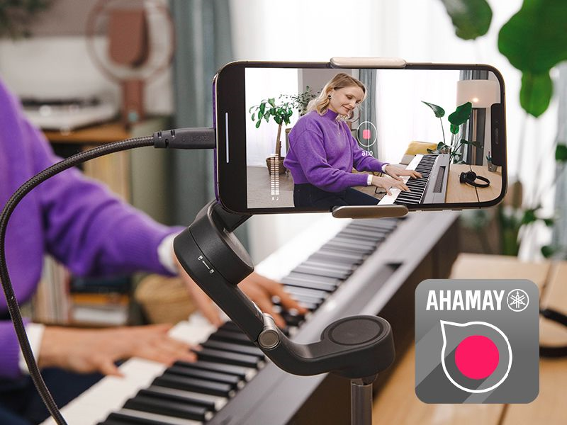 A view of the Yamaha Rec'n'Share app icon and a person taking a smartphone video of them playing